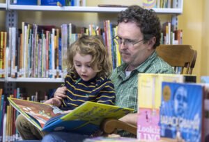 Jason Kave and his son, Ian, of Stanley, read a book in the children's section of the Kibler Library in Stanley