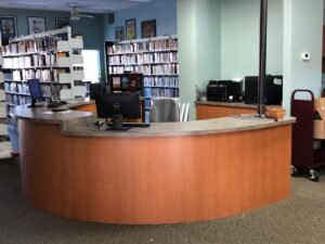Kibler Library reception desk with computers and bookshelves in the background