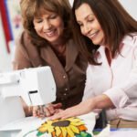 Two women quilting together in front of a sewing machine