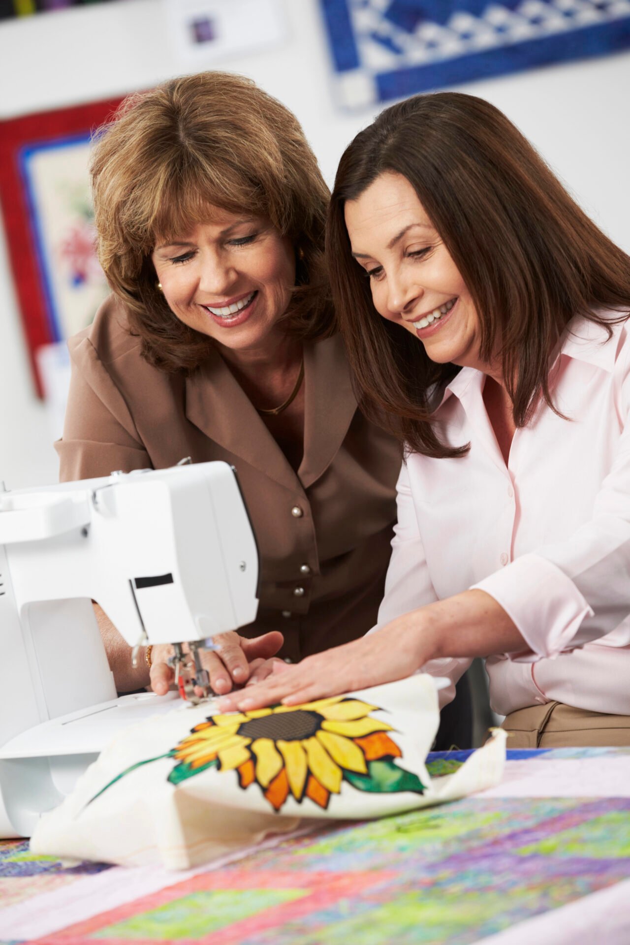 Two women quilting together in front of a sewing machine